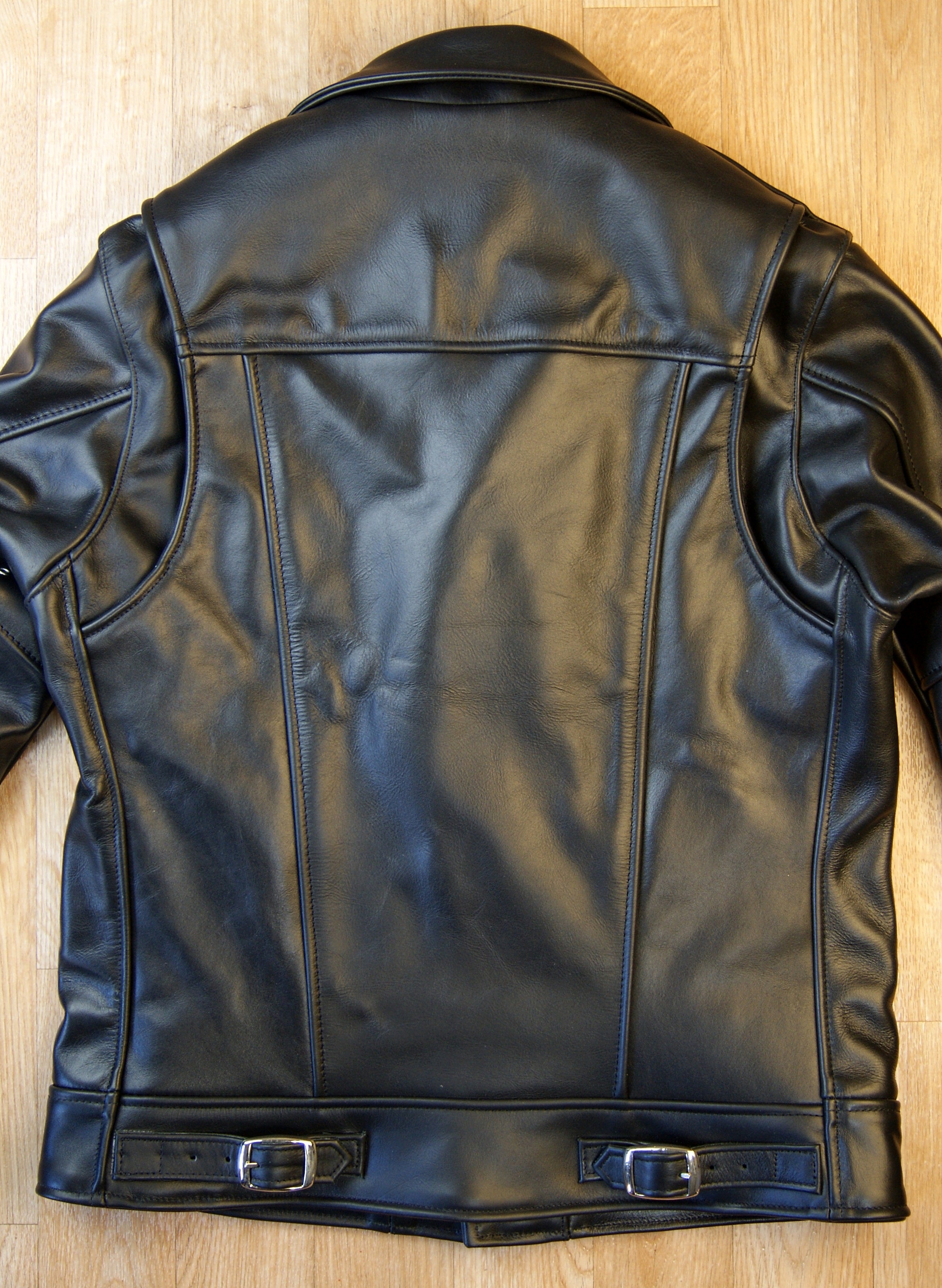 Black of black leather motorcycle jacket.  Shoulder gussets that open.  Small buckles at bottom hem.